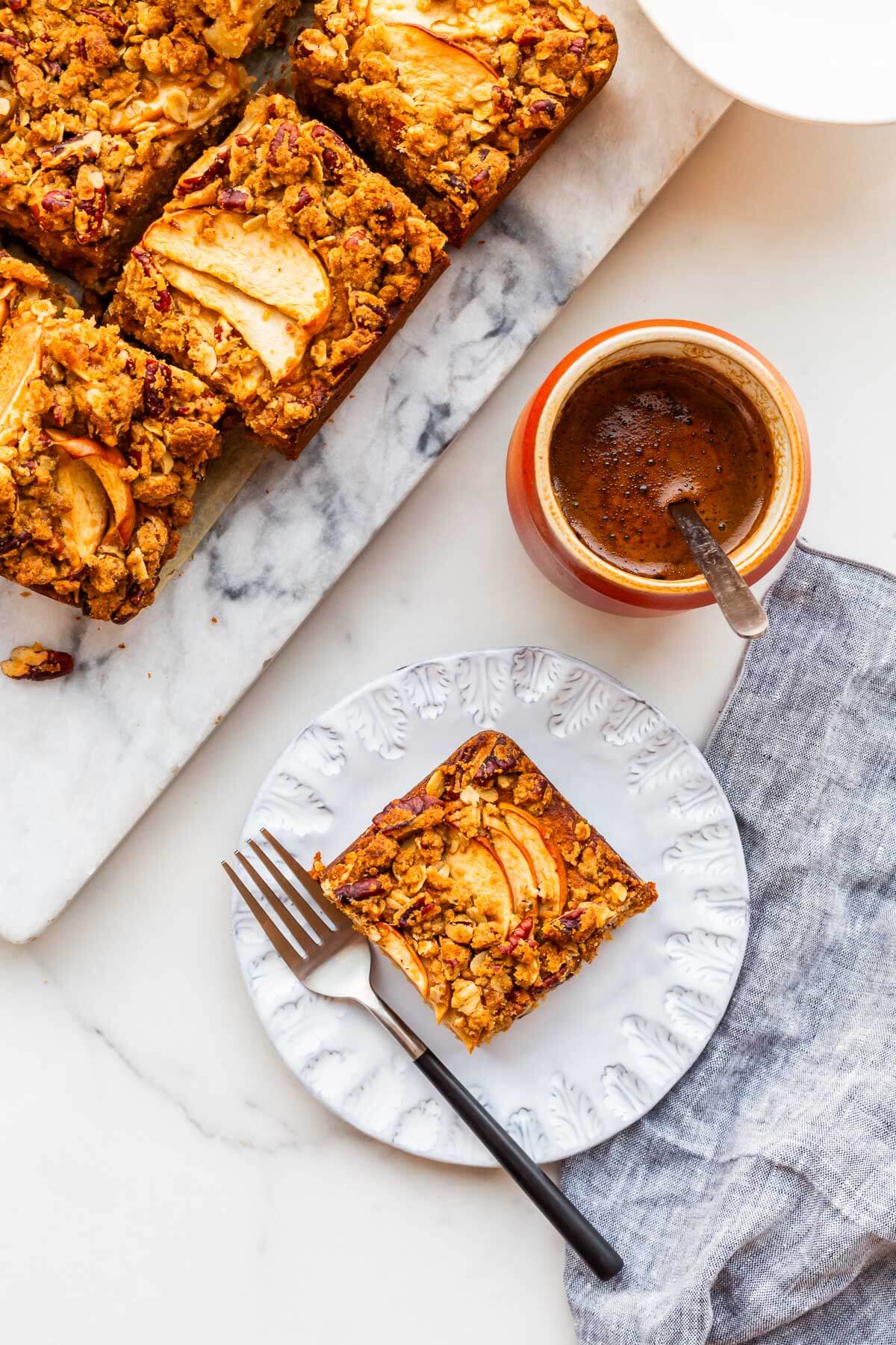 Squares of apple cake served with a cup of coffee.