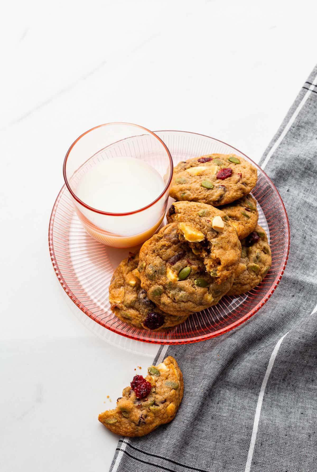 A plate of cranberry white chocolate chip cookies served with a glass of milk.