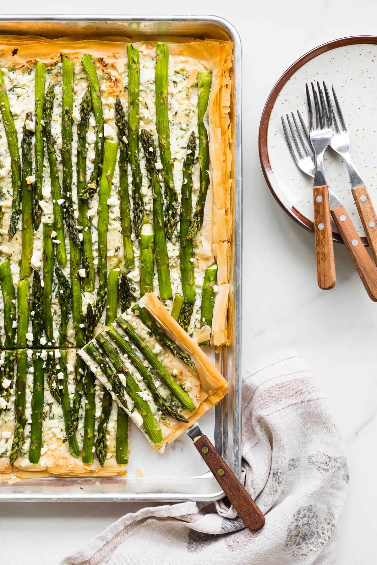 Serving an asparagus phyllo tart cut into squares.