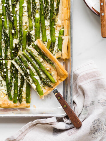 Serving an asparagus phyllo tart cut into squares.