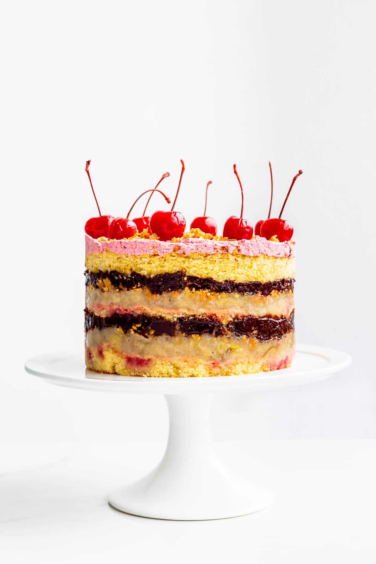 Banana split layer cake topped with maraschino cherries.