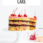Banana split layer cake topped with maraschino cherries on a cake stand.
