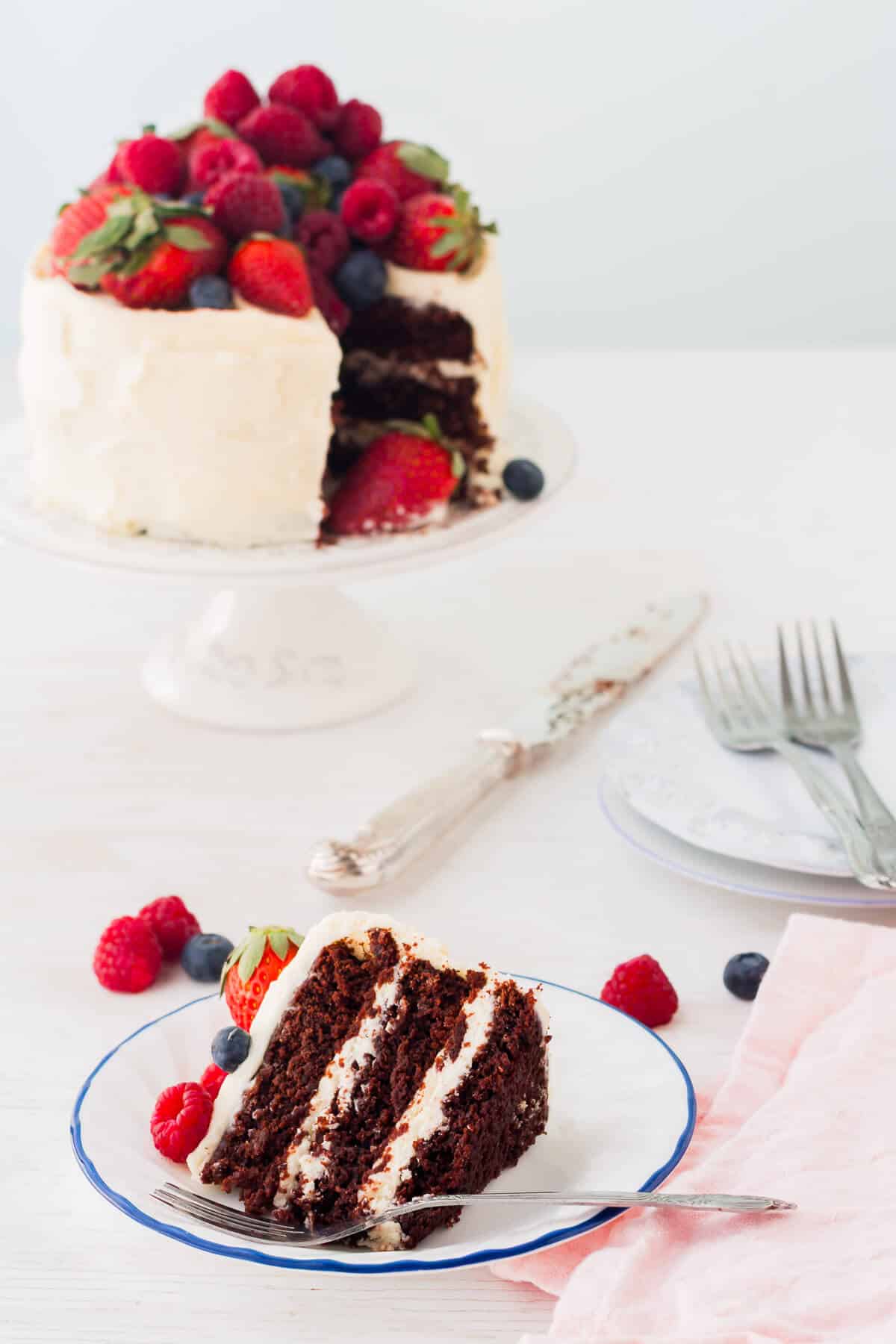 A slice of dark chocolate cake with berries on a small plate.