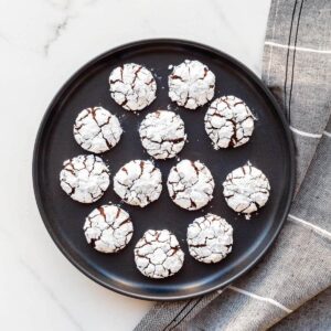 Chocolate crackle cookies arranged on a black plate.
