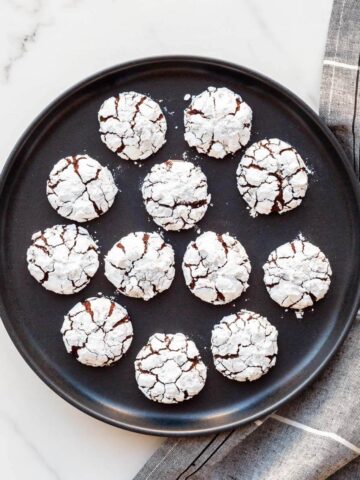 Chocolate crackle cookies arranged on a black plate.