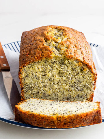 Slicing an orange cake with poppy seeds to serve it.
