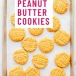 A sheet pan of peanut butter cookies with a criss-cross pattern on surface of each cookie.
