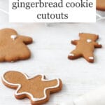 Gingerbread cookies being decorated with a piping bag of royal icing.