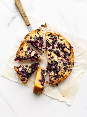 Sliced black currant cake on parchment paper with a wood-handled knife to serve