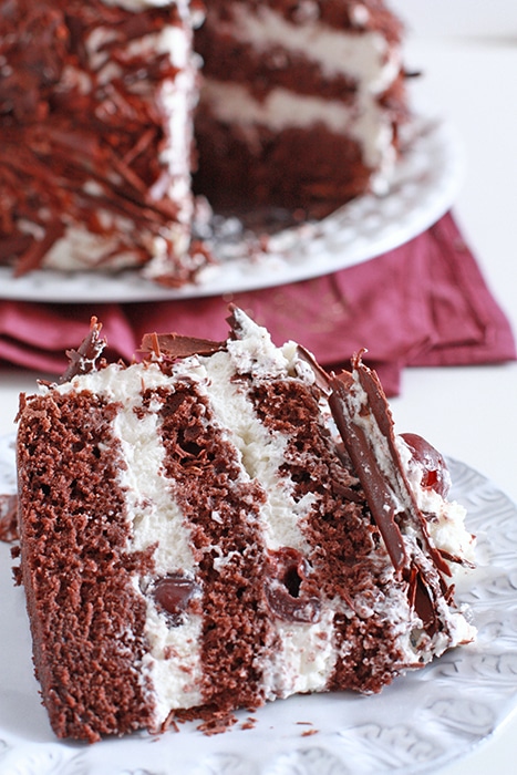 black forest cake sliced to show layers of chocolate sponge cake, whipped cream, and cherries