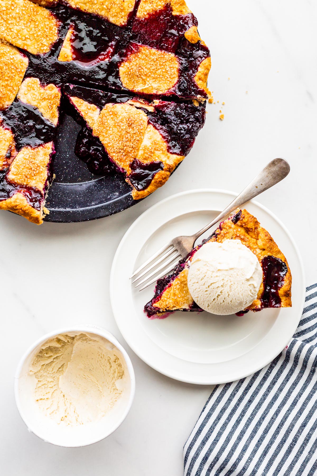 A slice of blueberry pie served à la mode with a scoop of vanilla ice cream on top, melting slowly.