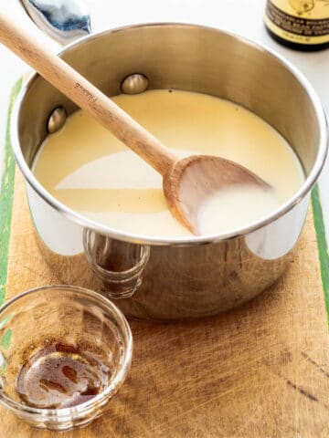 A saucepan of homemade crème anglaise (custard sauce) that is flavoured with vanilla bean paste.