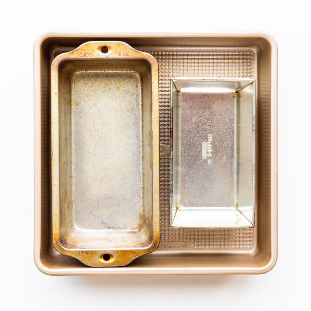 A stack of cake pans, one square and two rectangular loaf pans of different sizes.
