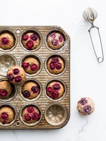 Dust cranberry chestnut financiers with powdered sugar