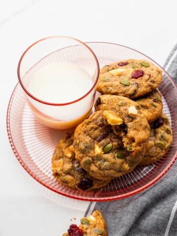 A glass of milk served with apple butter, cranberry, white chocolate chip cookies.