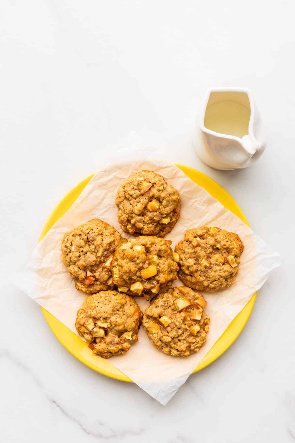 A plate of apple oatmeal cookies served with milk.