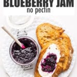 A jar of homemade blueberry jam served with cream cheese and toasted sourdough on a plate.