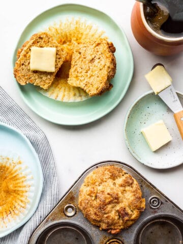 Freshly baked carrot muffins being served on plates with butter.