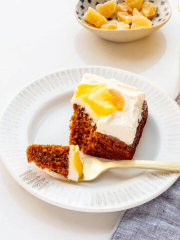 A piece of gingerbread cake with cream cheese frosting and lemon curd served on a dessert plate.