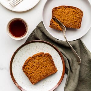 Slices of pumpkin bread served on dessert plates with a cup of coffee.