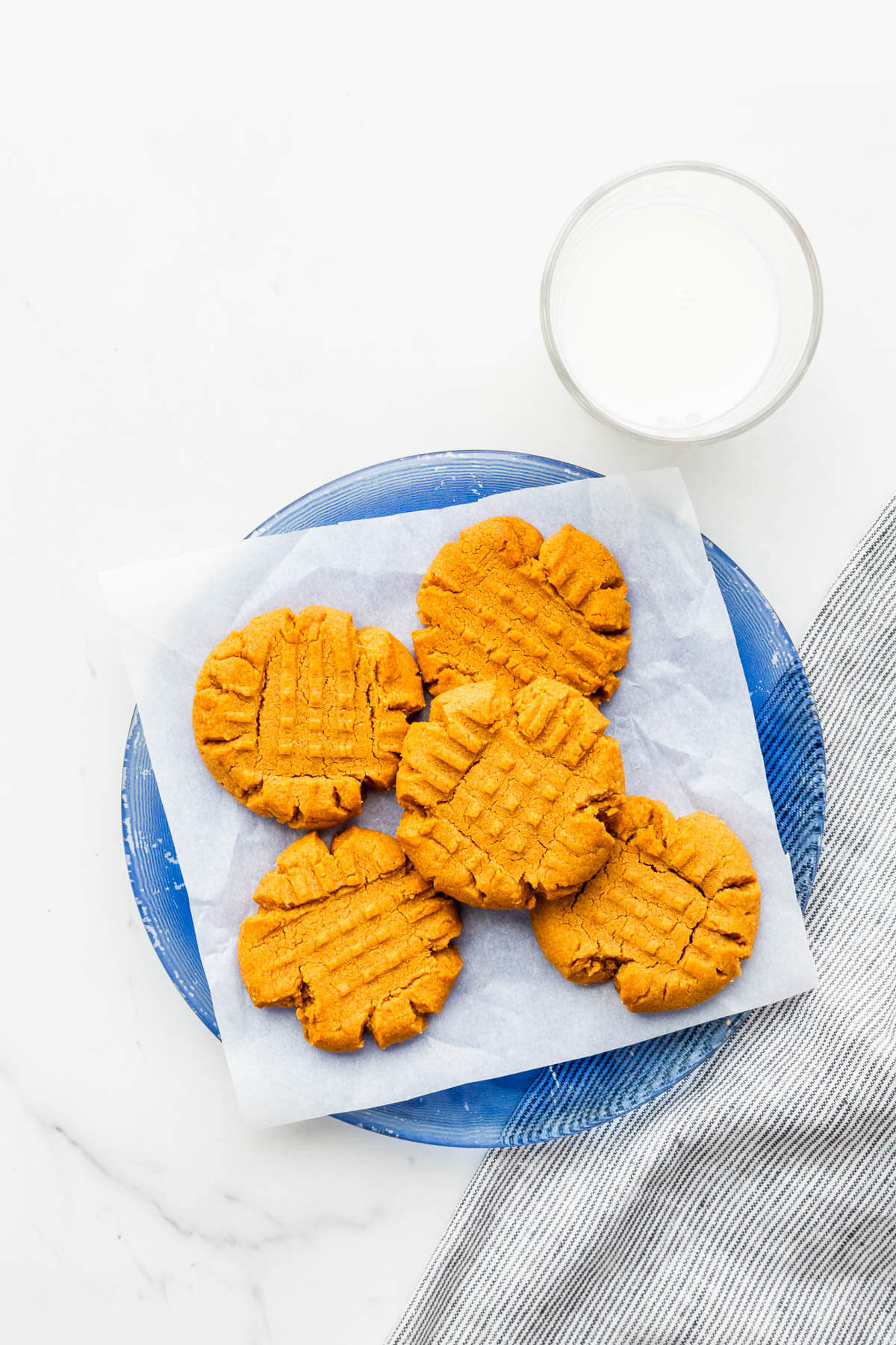 A plate of flourless peanut butter cookies served with a glass of milk.