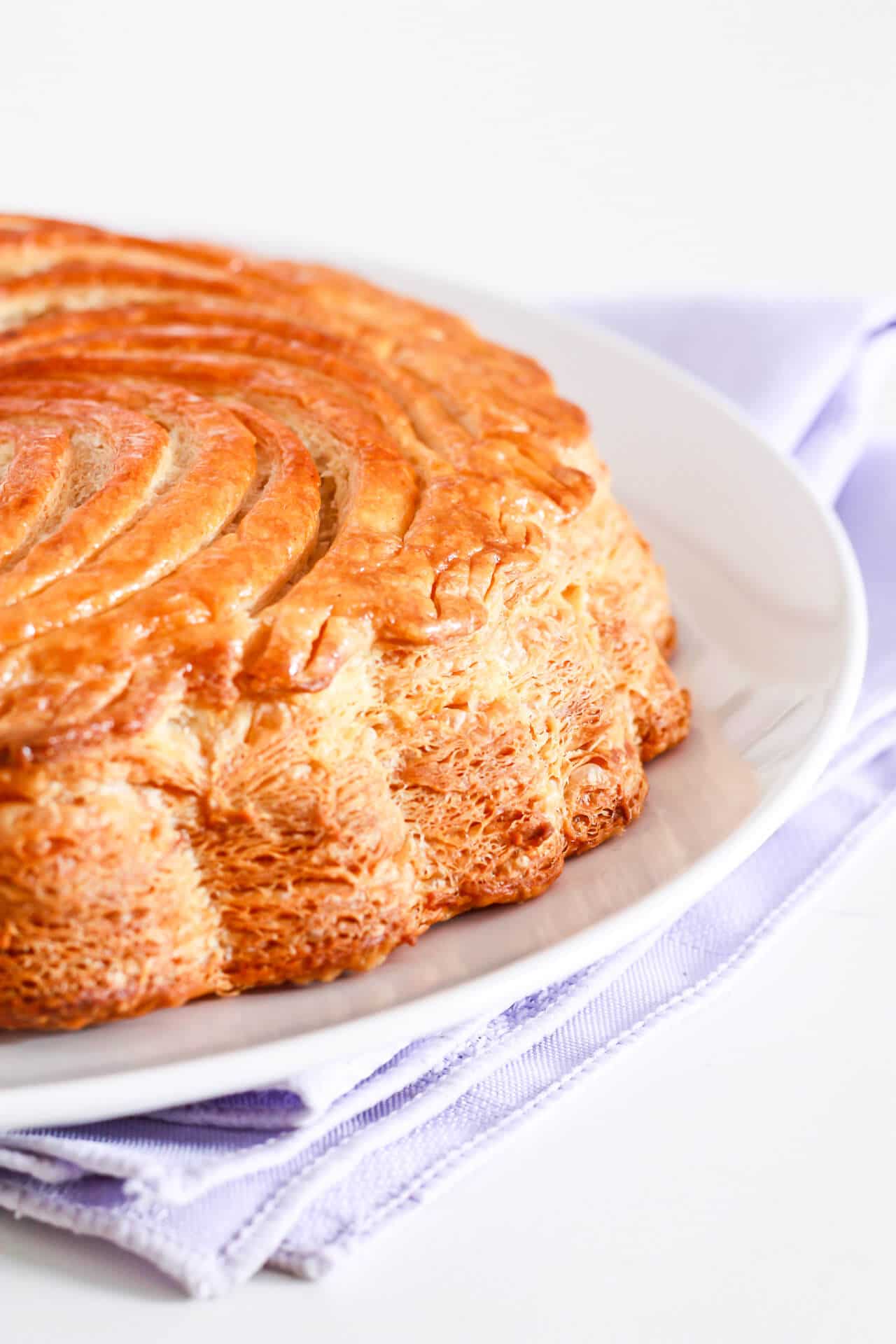 Galettes des rois (pithiviers) with a scalloped edge set on a white plate on a purple linen napkin