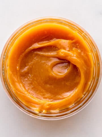 A jar of homemade milk jam viewed from the top to show the gooey, thick texture.