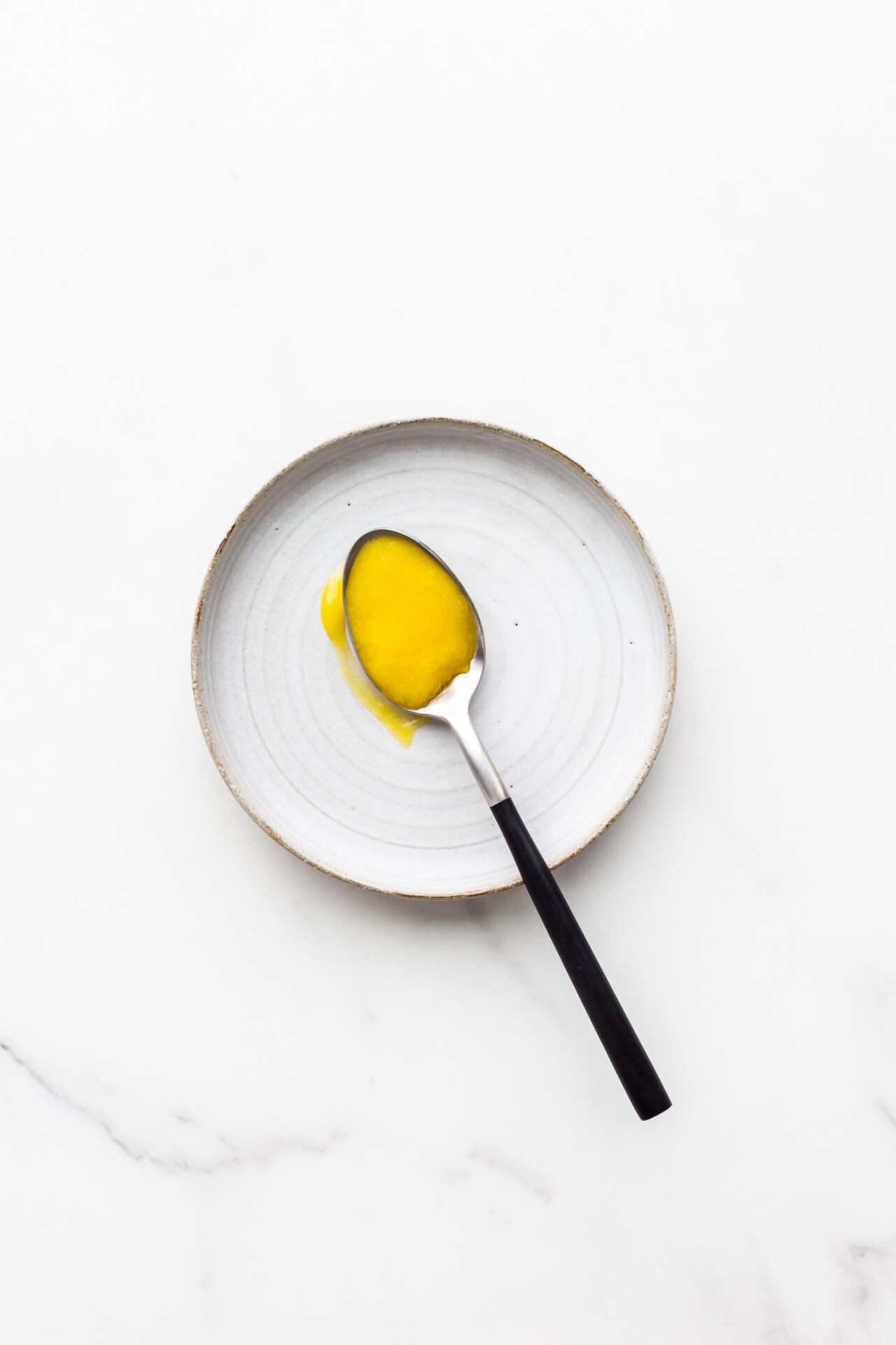 A spoonful of lemon curd set on a plate.