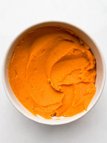 A bowl of smooth, cooked sweet potato purée ready for baking.
