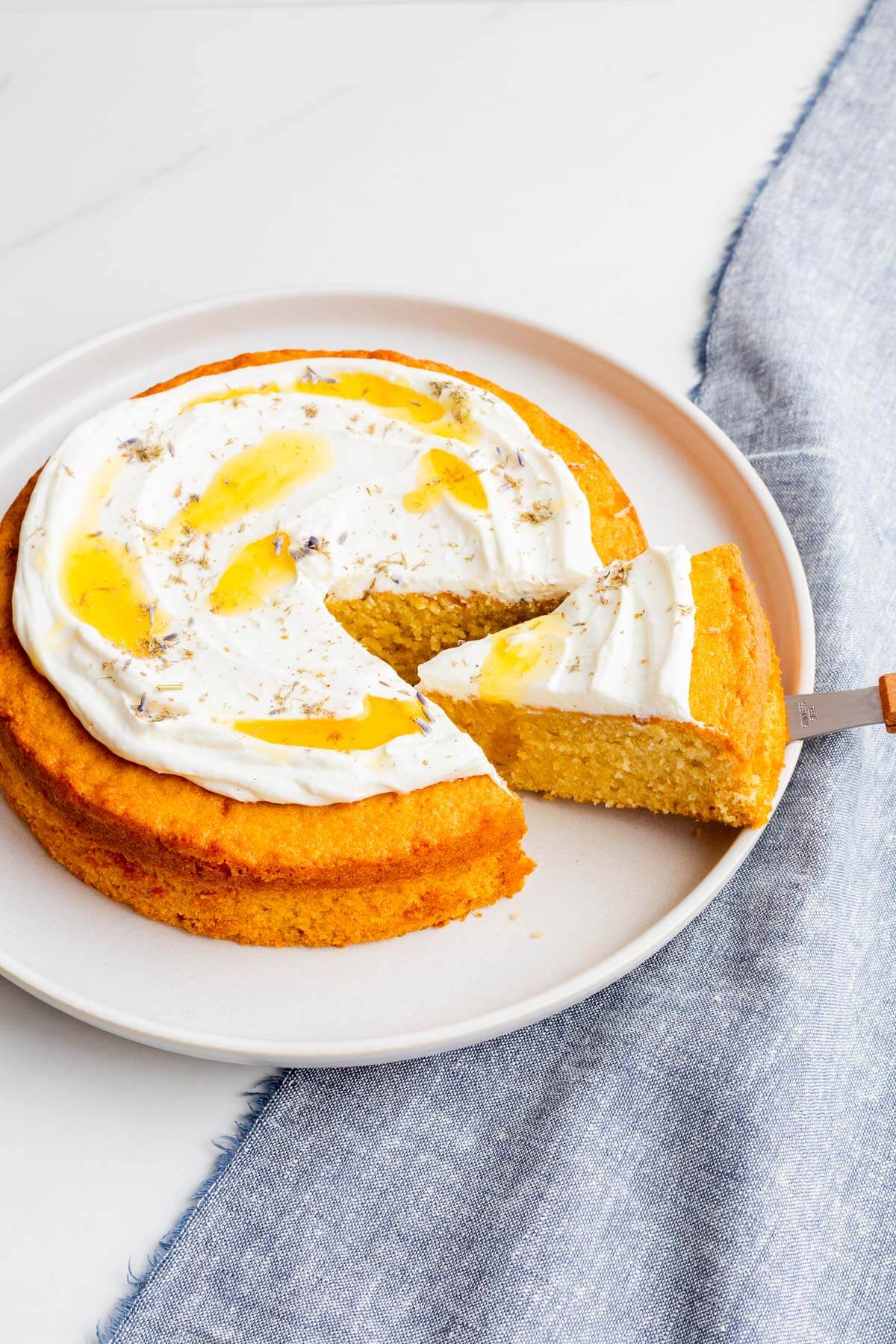 Slicing and serving a honey cake topped with whipped cream.