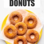 A yellow plate of baked pumpkin donuts coated in cinnamon sugar.