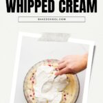 Spreading whipped cream over a layer of berries and pastry cream in a glass bowl for trifle.