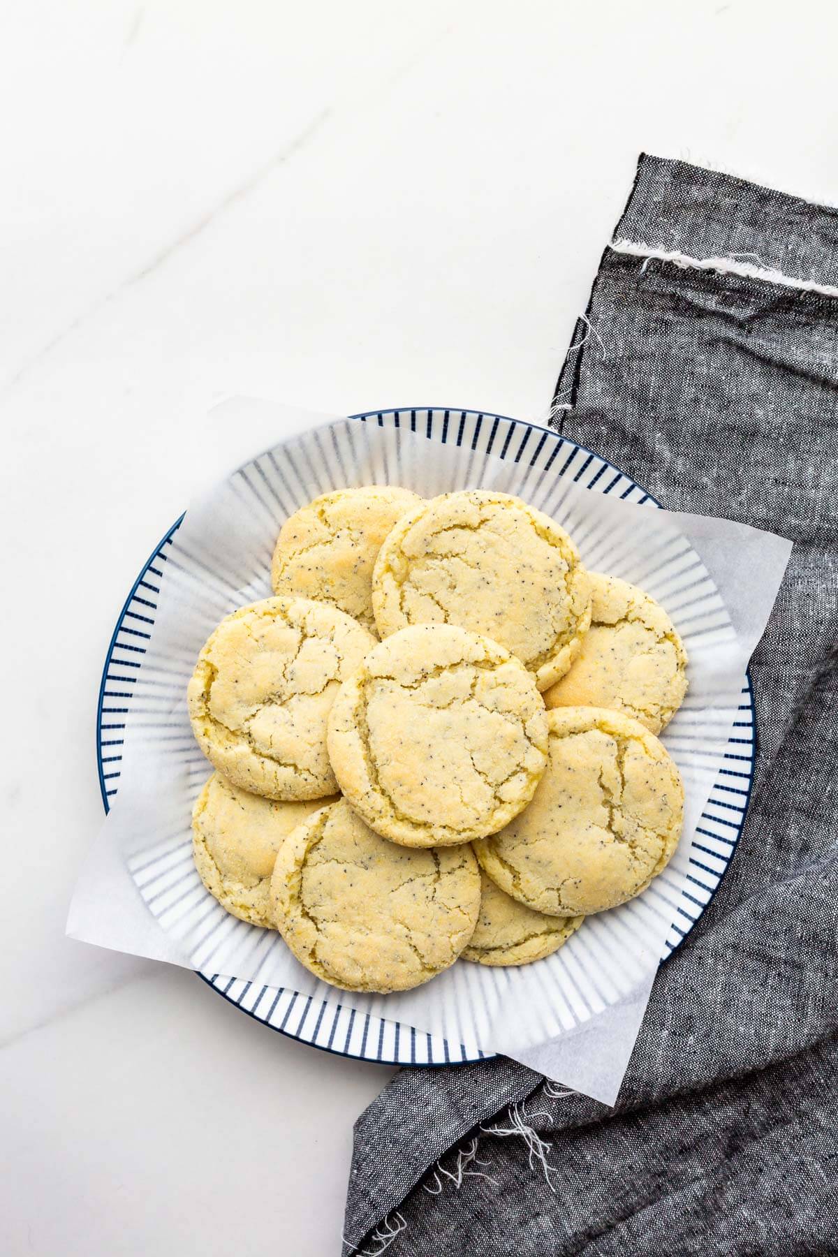 A plate of lemon poppy seed cookies with a grey denim napkin.