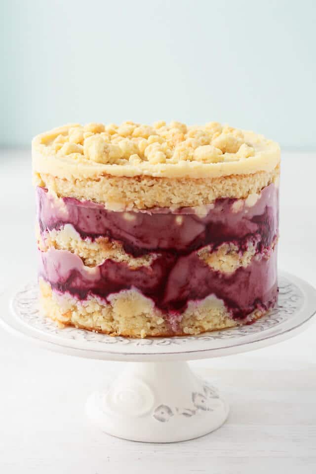 Milk crumbs on a Momofuku Milk Bar style cake-layers of purple blackberry curd, cream coloured almond cake, and creamy almond frosting