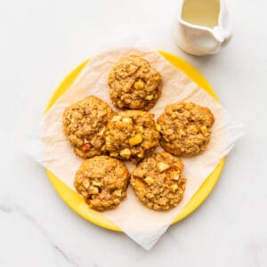 A plate of apple oatmeal cookies served with milk.