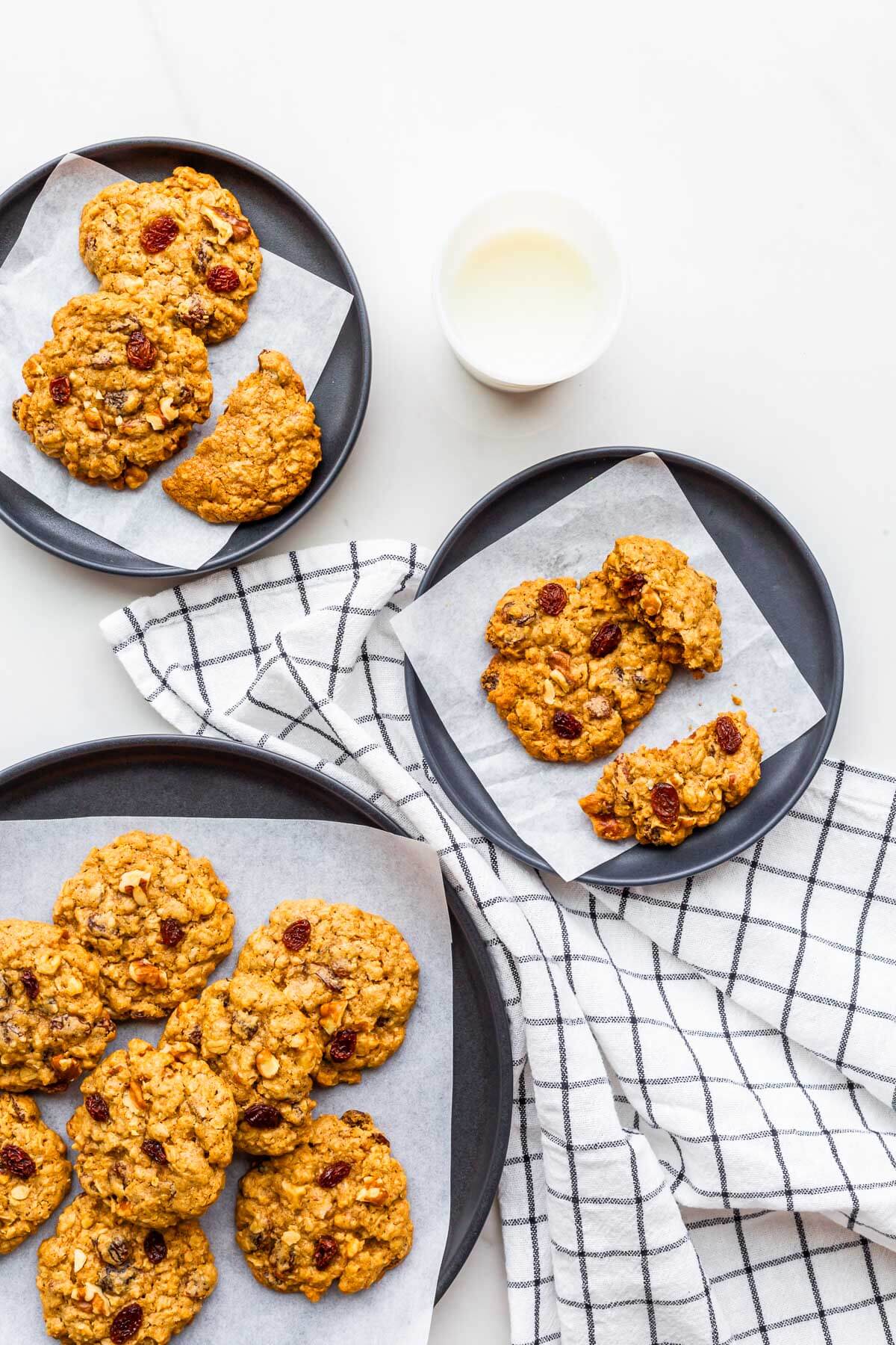 Plates of oatmeal raisin cookies served with a glass of milk.