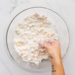 Making pie crust by hand in a bowl.