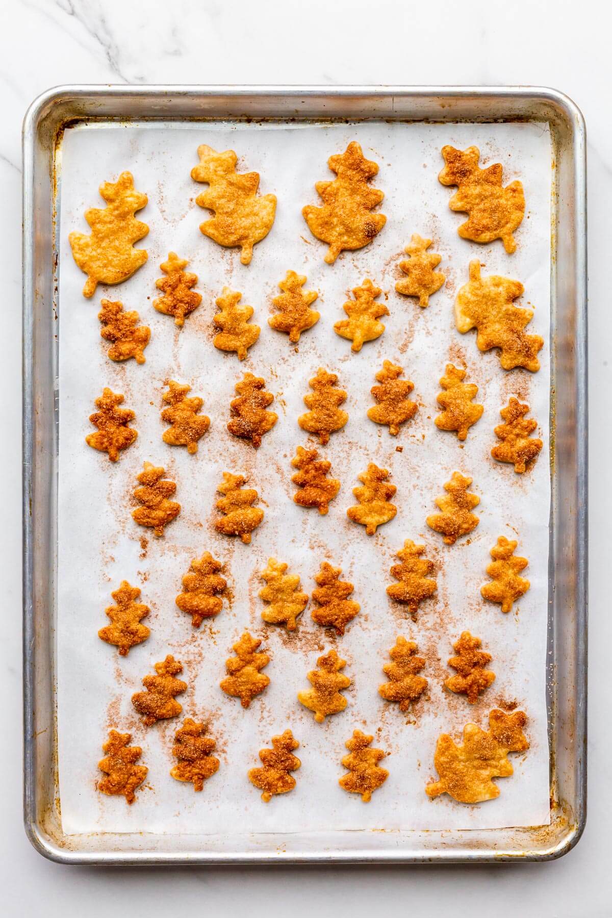Baked leaf cookie cutouts made from leftover pie dough topped with cinnamon sugar for decorating pumpkin pie.