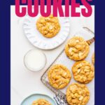 White chocolate macadamia cookies being served with glasses of milk.