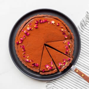 Cutting a chocolate ganache tart into slices to serve it.