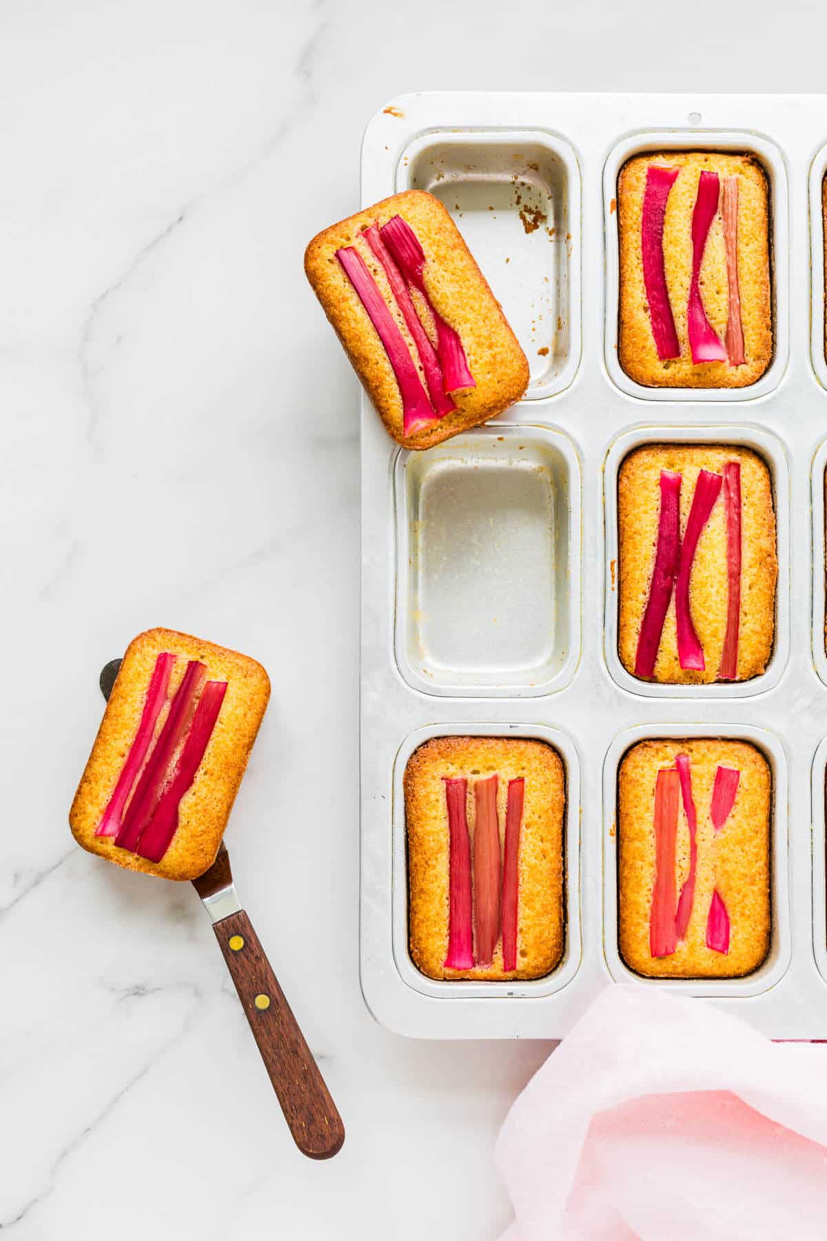 Unmoulding rhubarb cakes from mini loaf pans with a mini offset spatula.