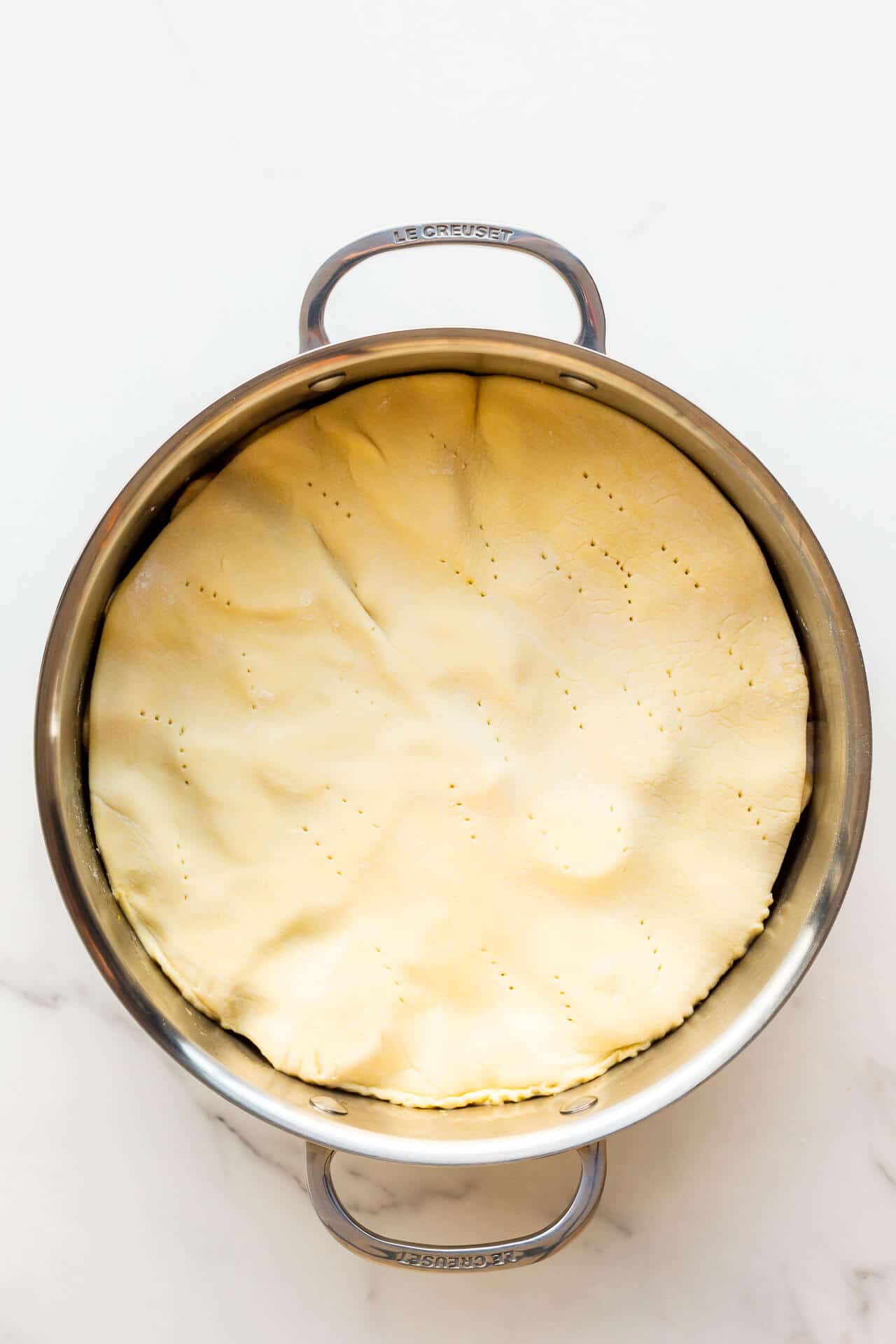 A pan with apples topped with pastry ready to be baked to make an apple tarte tatin.