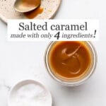 A jar of homemade salted caramel sauce made from only 4 ingredients, with a little bowl of flaky sea salt on the side and a ceramic plate with a spoonful of caramel