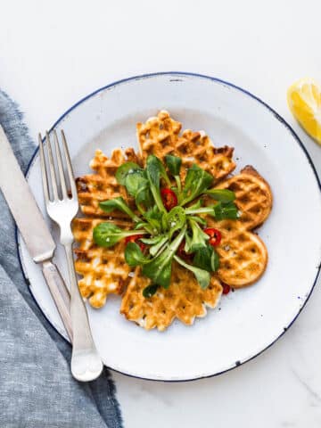 A plate of cheese waffles served with greens.