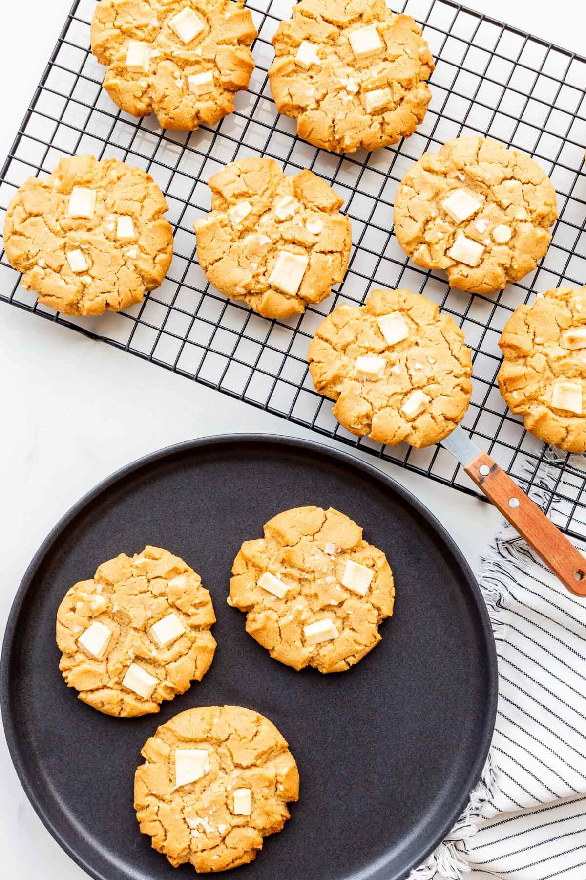 Peanut butter cookies on a cooling rack next to a plate of cookies.