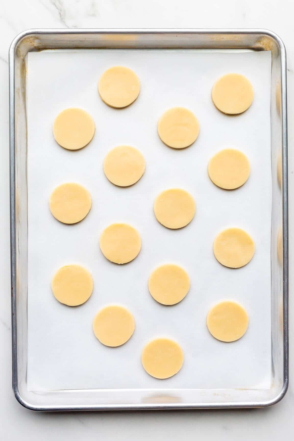 Shortbread cookie cutouts before baking on a sheet pan lined with parchment.