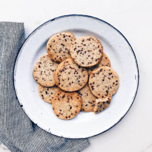 A plate of shortbread cookies with flecks of cocoa nibs.