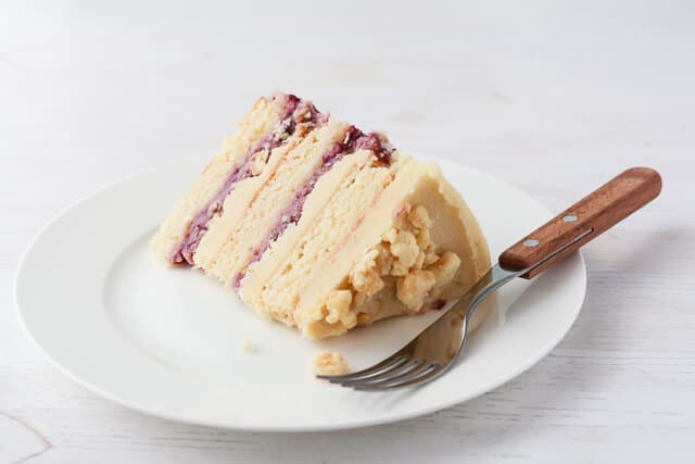 Slice of Momofuku Milk Bar style cake-layers of blackberry curd, almond cake, and almond frosting