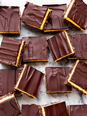 Nanaimo bars cut into squares and served on a marble surface.