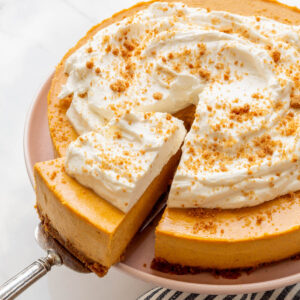 Serving a slice of pumpkin cheesecake topped with whipped cream.